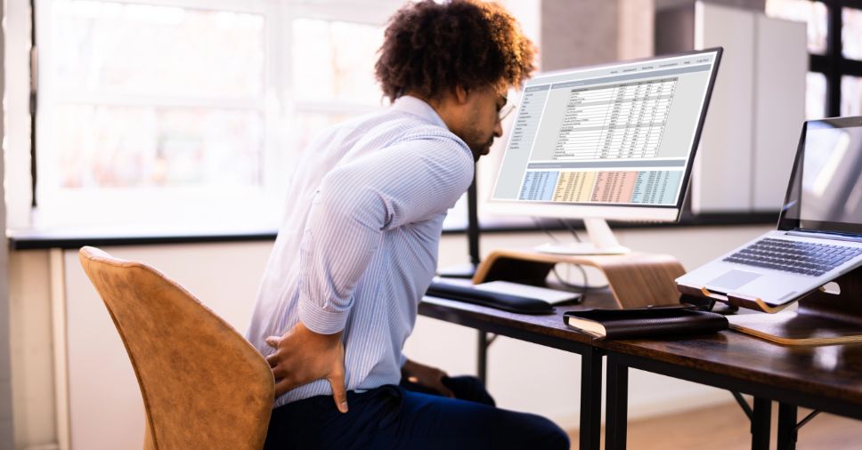 Homem com dores lombares precisa investir em uma boa ergonomia para escritório no dia a dia.