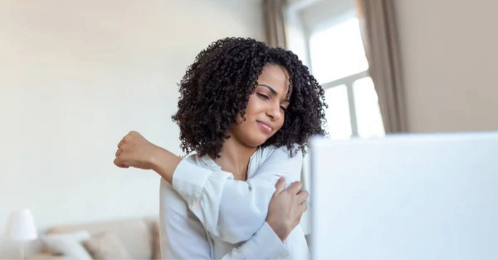 Profissional puxa o braço em pausa de alongamento de ergonomia para profissionais mais velhos.